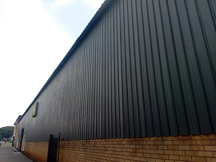 Long industrial wall finished in grey coating above face brick