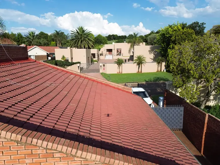Freshly recoated red tile roof sweeping across the frame under blue sky